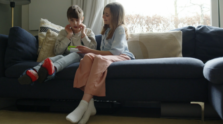 broertje en zusje aan het gamen zittende op de bank