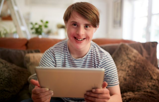 Jongen met verstandelijke beperking met iPad op schoot