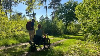Twee wandelaars, lopen over het Pieterpad, waarvan een in een off-the-road rolstoel