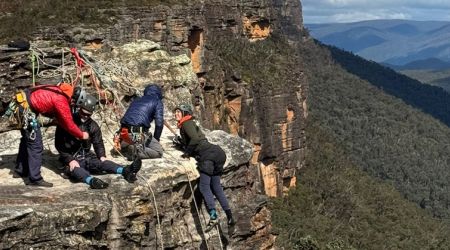Vier bergbeklimmers, waarvan 2 met een dwarslaesie, bij een steile helling