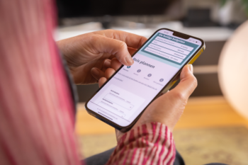 Een persoon met een mobiele telefoon die via de Vita app een taxi boekt
