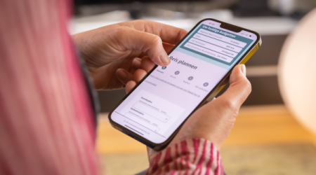Een persoon met een mobiele telefoon die via de Vita app een taxi boekt