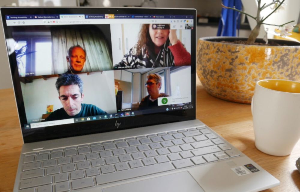 Een online vergadering. Een laptop met 4 gezichten van deelnemers aan de vergadering.