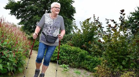 Mevrouw aan het wandelen met nordic walking stokken