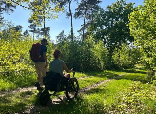 Twee wandelaars, lopen over het Pieterpad, waarvan een in een off-the-road rolstoel