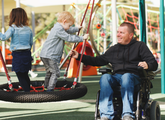 Vader in rolstoel met kind in een speeltuin