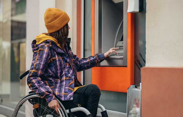 Persoon in een rolstoel bij een pinautomaat