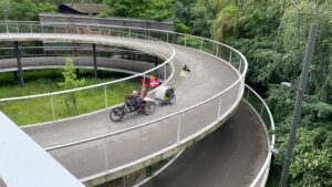 Astrid op haar handbike gaat een spiraalvormige fietshelling af