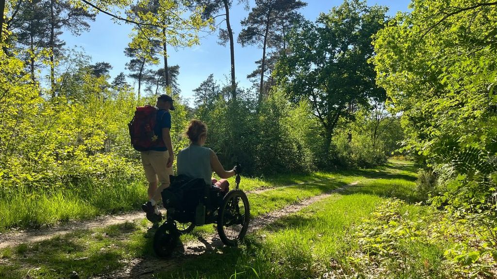 Twee wandelaars, lopen over het Pieterpad, waarvan een in een off-the-road rolstoel