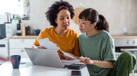 Twee personen met een laptop met belastingpapieren in hun hand