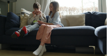 broertje en zusje aan het gamen zittende op de bank