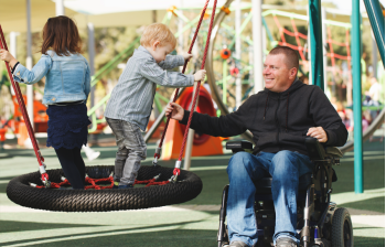 Vader in rolstoel met kind in een speeltuin