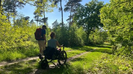 Twee wandelaars, lopen over het Pieterpad, waarvan een in een off-the-road rolstoel
