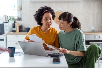 Twee personen met een laptop met belastingpapieren in hun hand