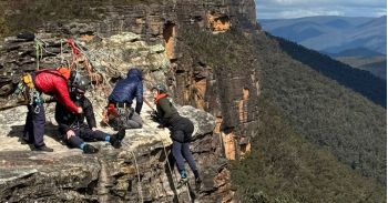 Vier bergbeklimmers, waarvan 2 met een dwarslaesie, bij een steile helling