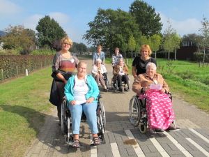 Personen in een rolstoel die geduwd worden tijdens een wandeling